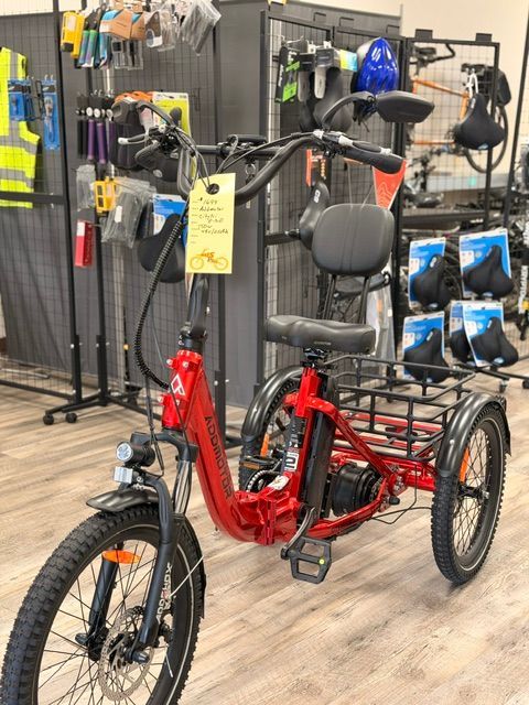 Red three-wheeled electric tricycle on display in a bike shop.