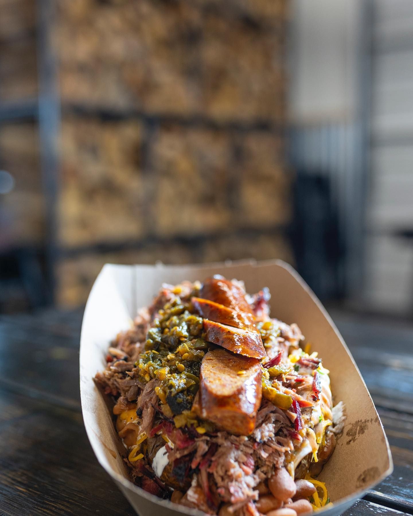 Tray of loaded fries topped with chopped meat, herbs, and sauce on a table