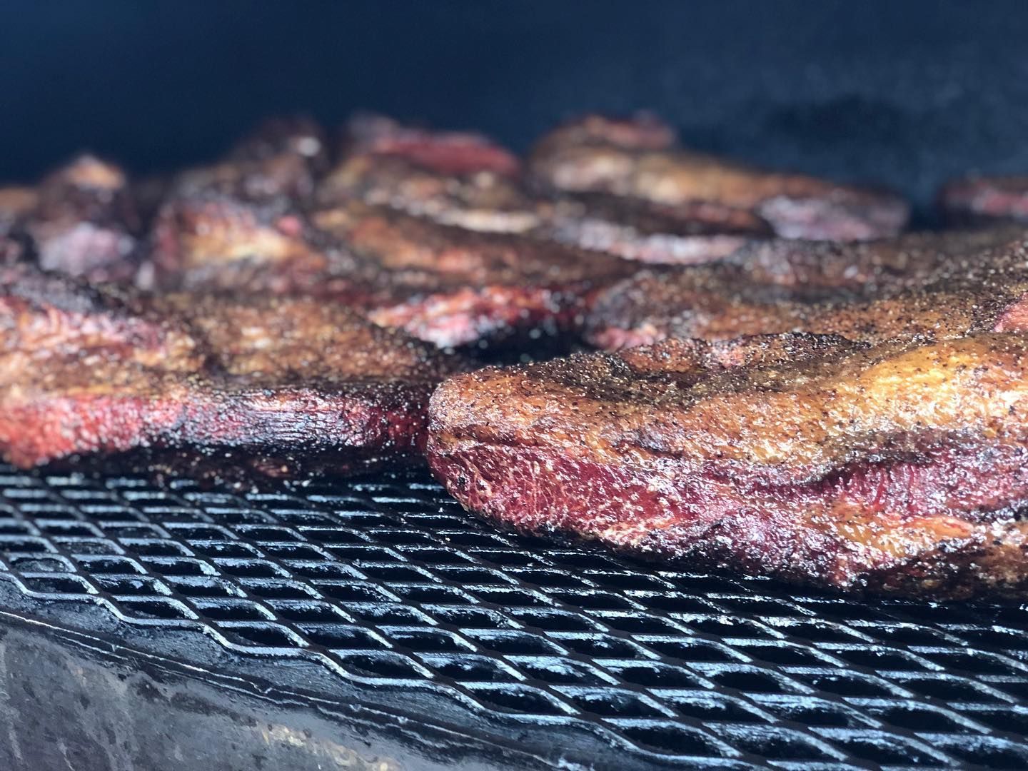 Steaks sizzling on a grill, with charred surfaces and smoke rising
