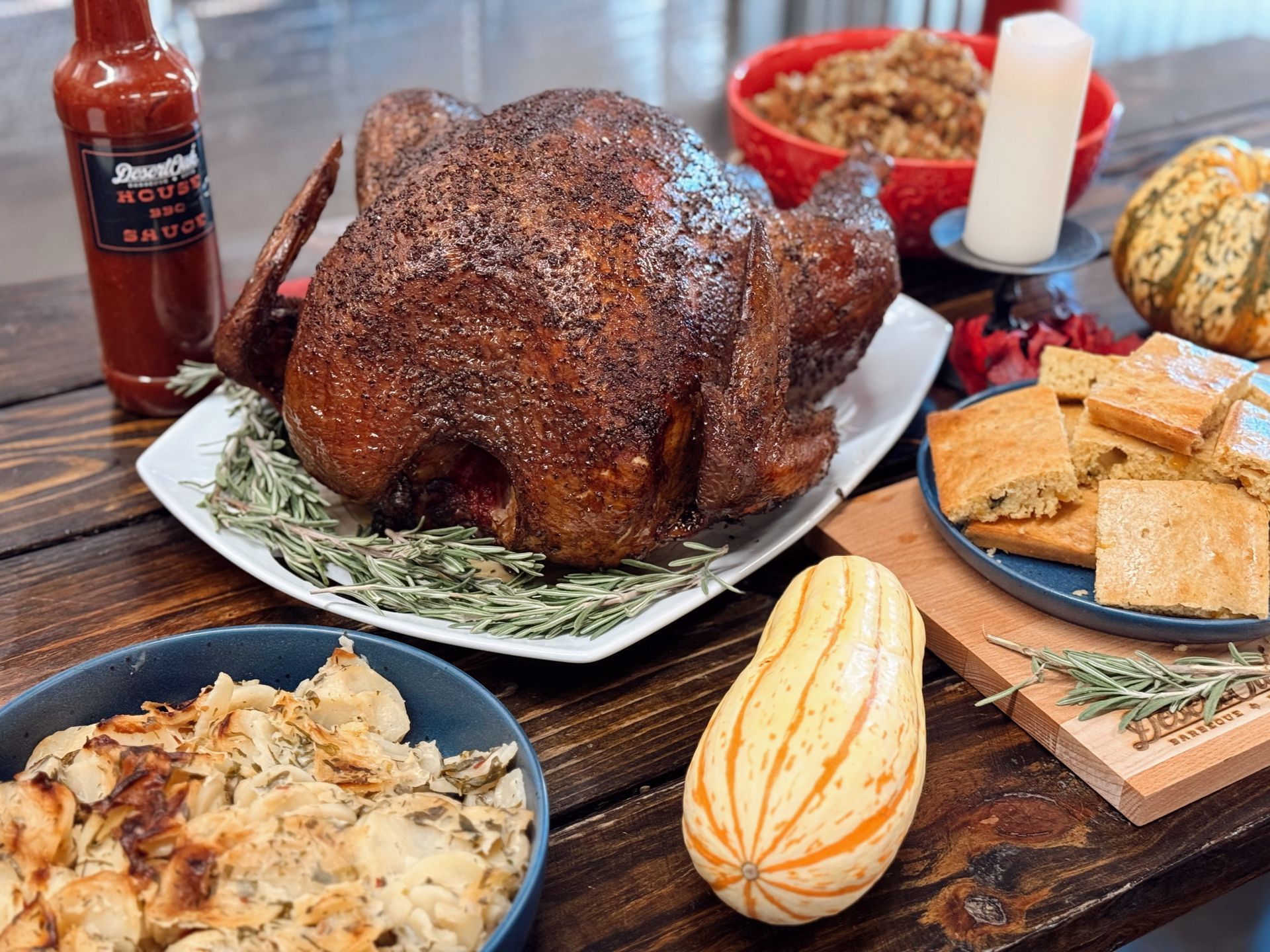 Roasted turkey centerpiece with side dishes, rolls, sauce, and candle on a holiday table