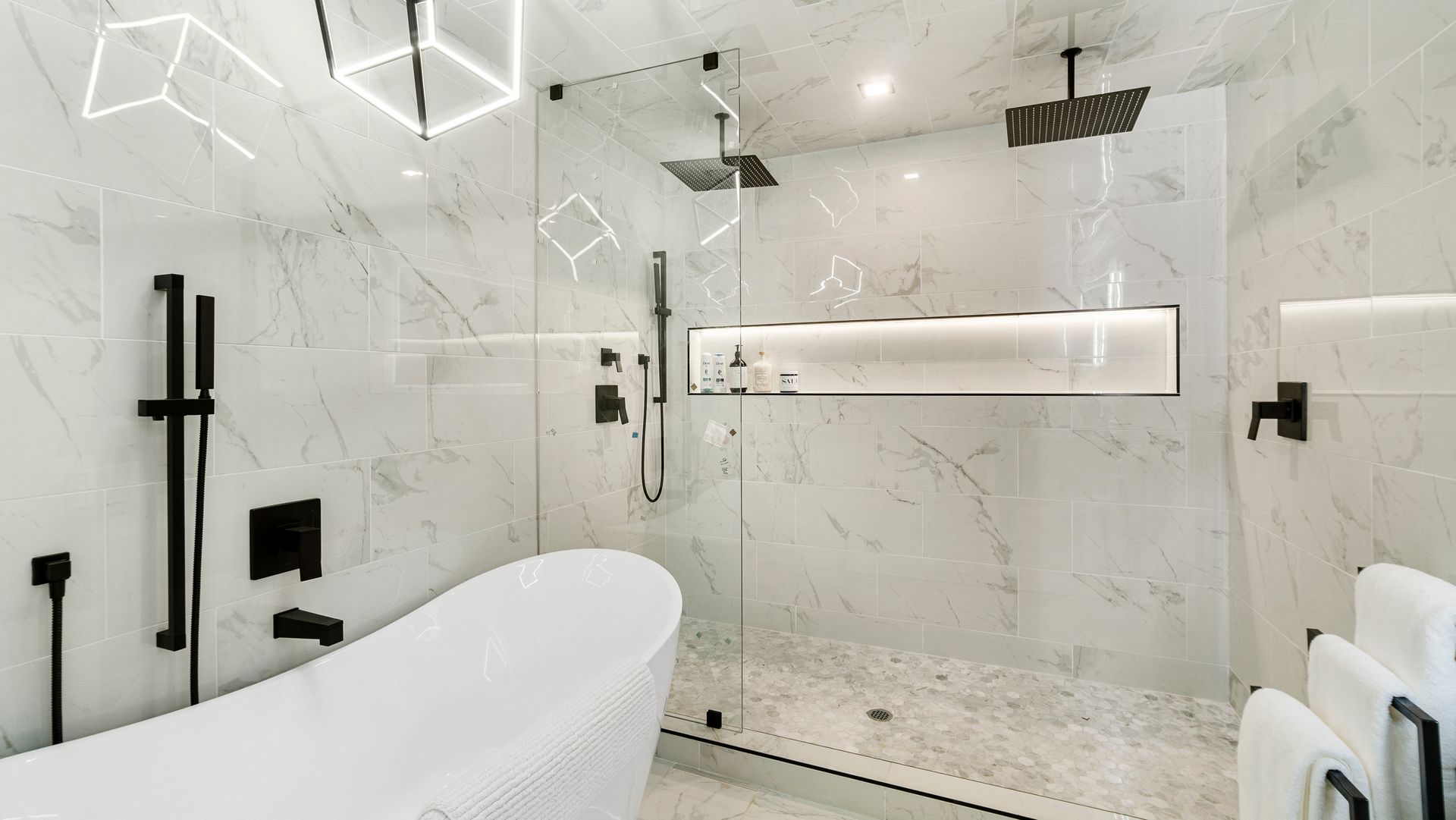 Modern white bathroom with a freestanding tub, glass shower, and marble-style walls