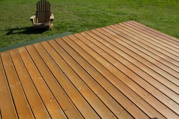 Wooden deck overlooking a grassy yard with a single Adirondack chair in the background