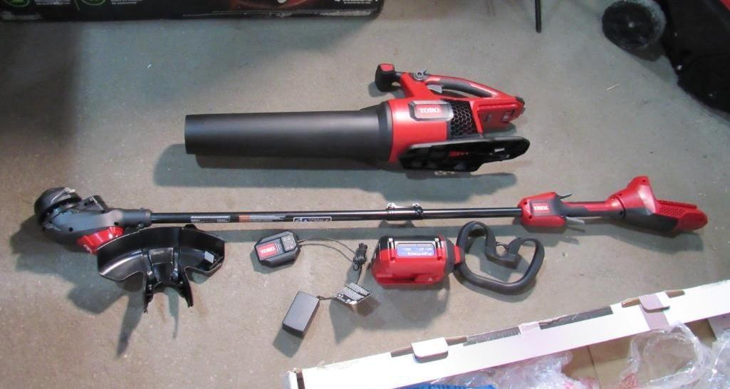 Disassembled red and black lawn equipment: blower, trimmer, and accessories, laid on floor.