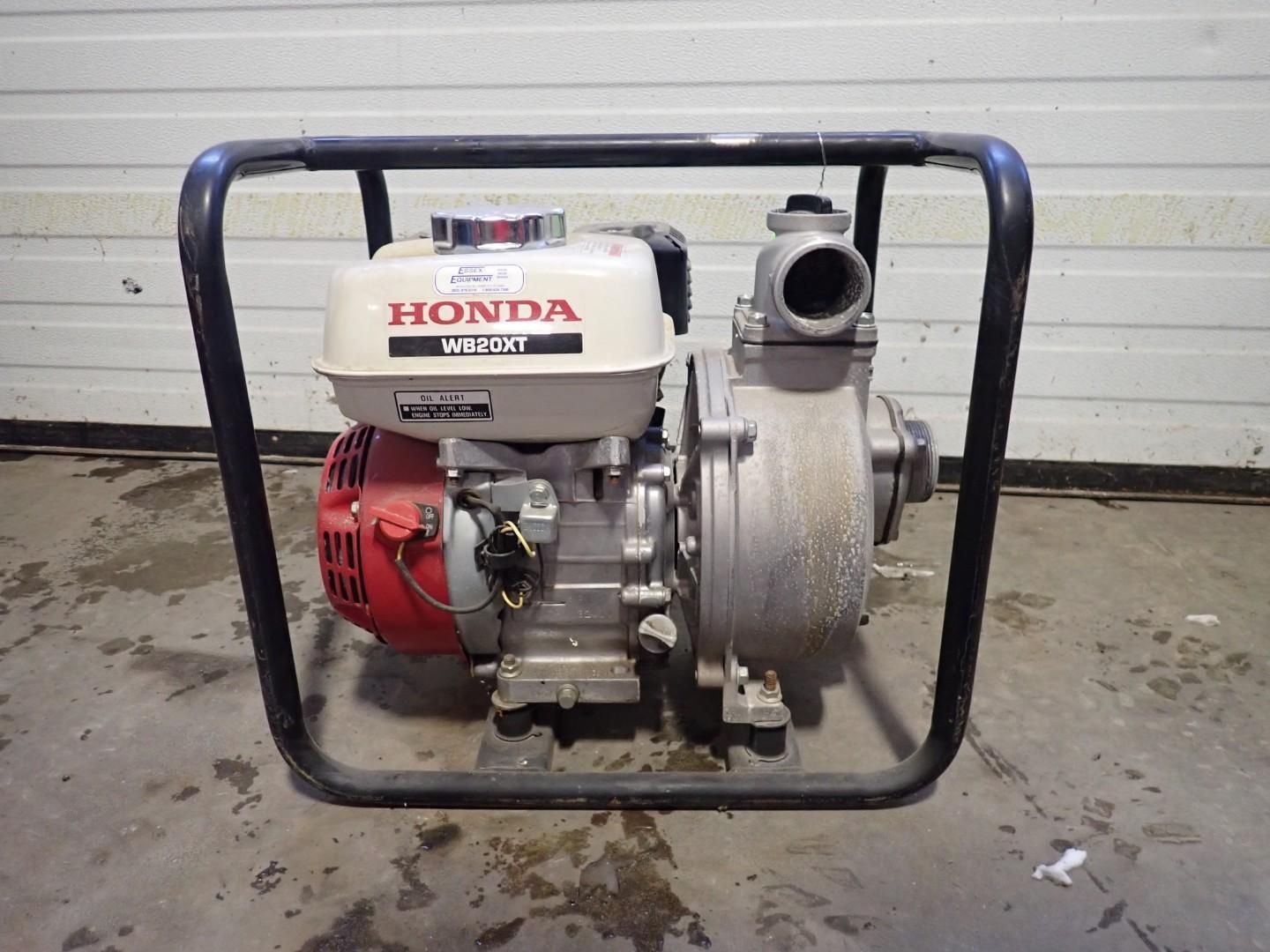 A Honda-powered portable water pump inside a black metal protective frame, sitting on a concrete floor.