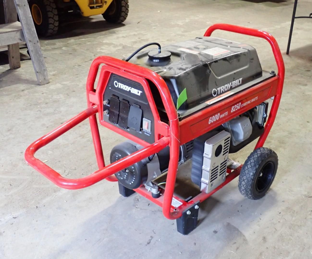 A portable Troy-Bilt 6250-watt red frame generator with wheels, resting on a concrete floor.