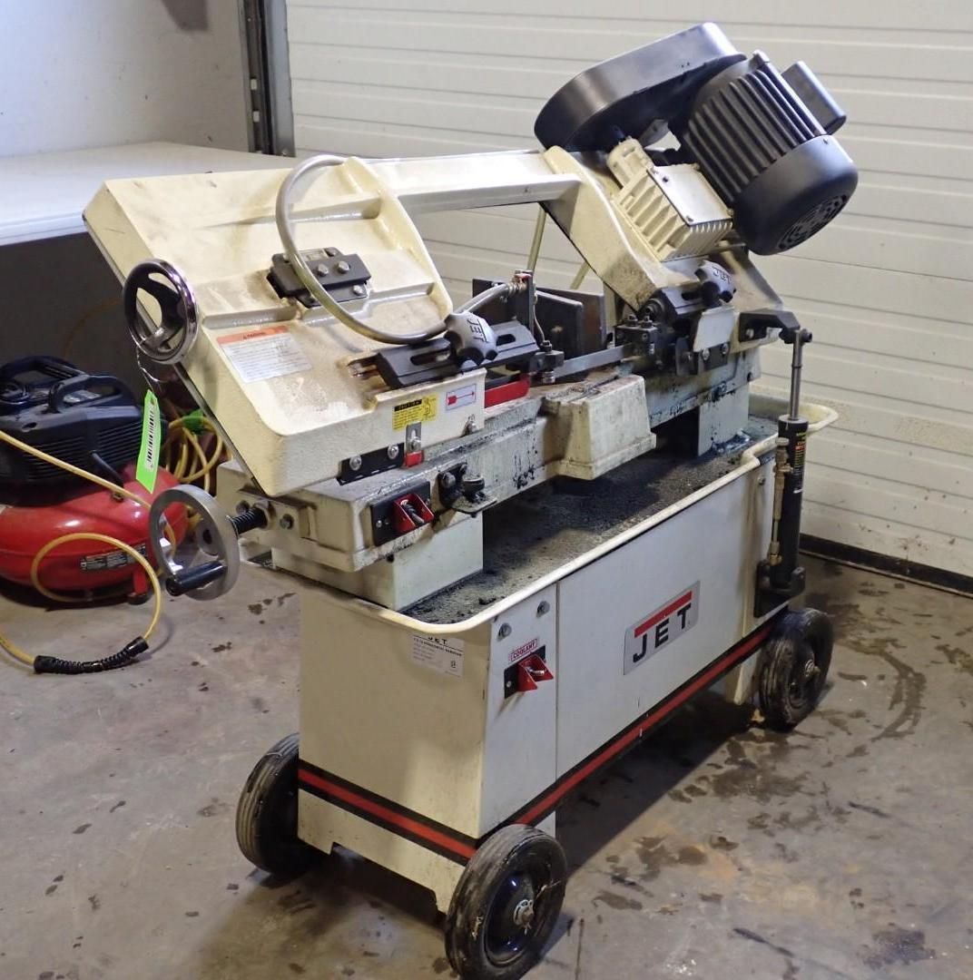 A cream-colored JET metal-cutting bandsaw on a wheeled base, positioned in a workshop.