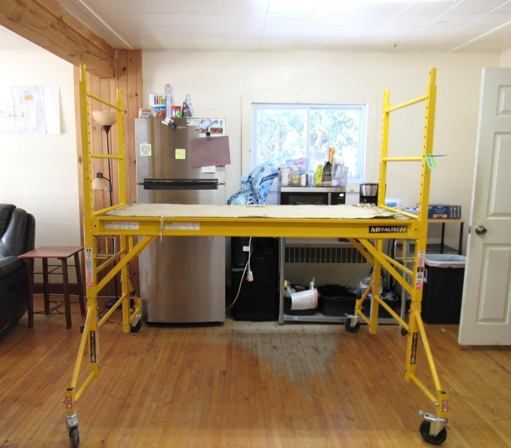 Yellow scaffolding with a wooden platform.