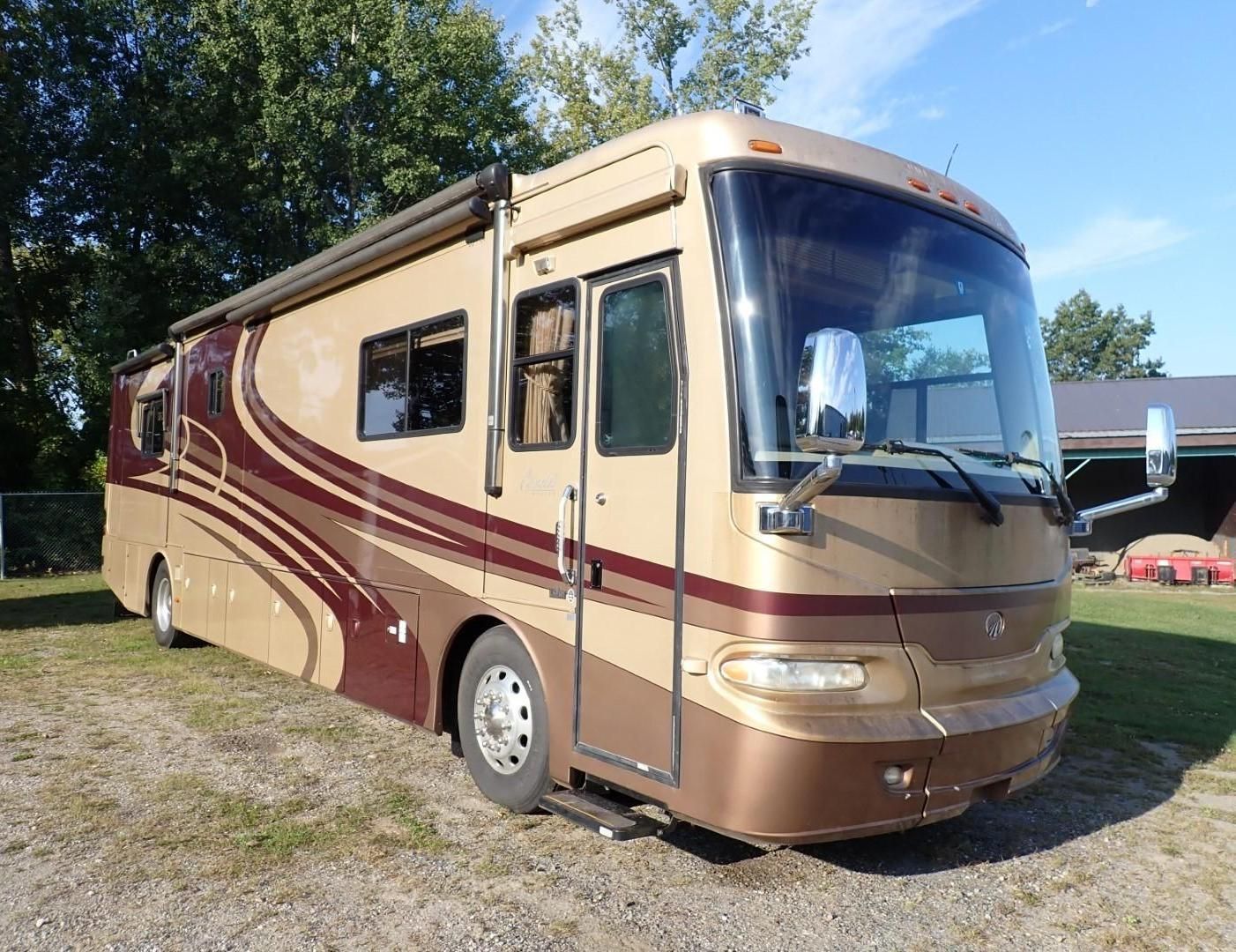 Tan and maroon RV parked on grass.