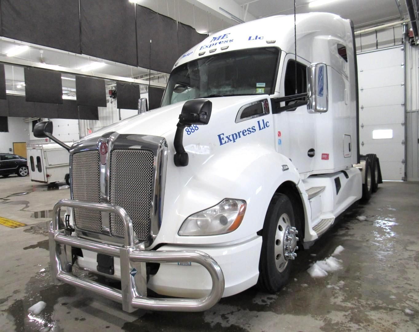 White semi-truck with chrome grill and bumper, parked inside a building.