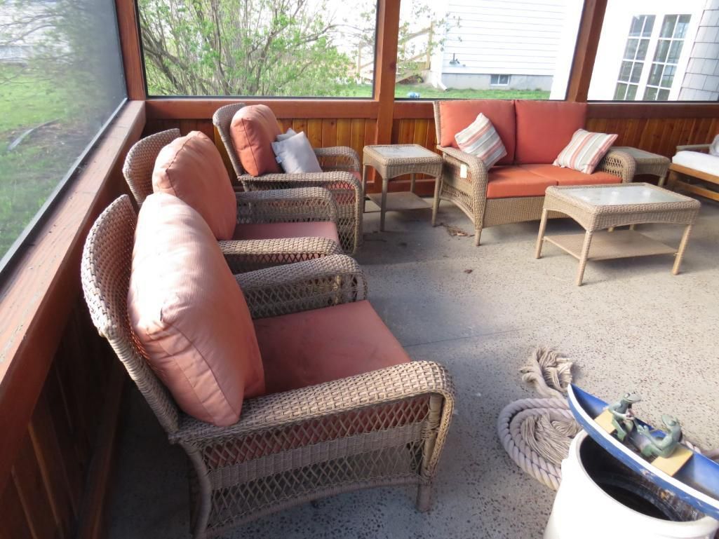Screened porch with wicker furniture and coral cushions.