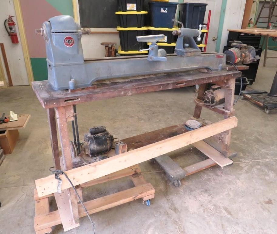 Wood lathe on a wooden workbench in a workshop. Gray machine, wood and metal.