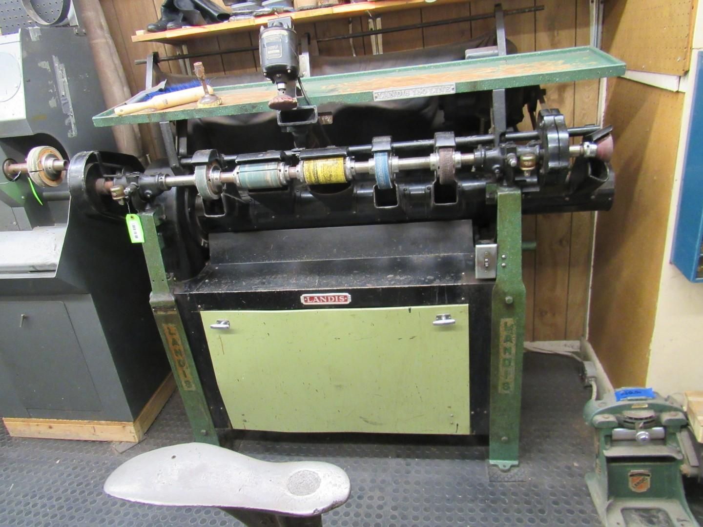 Industrial machine with rotating parts, green and black, in a workshop setting.