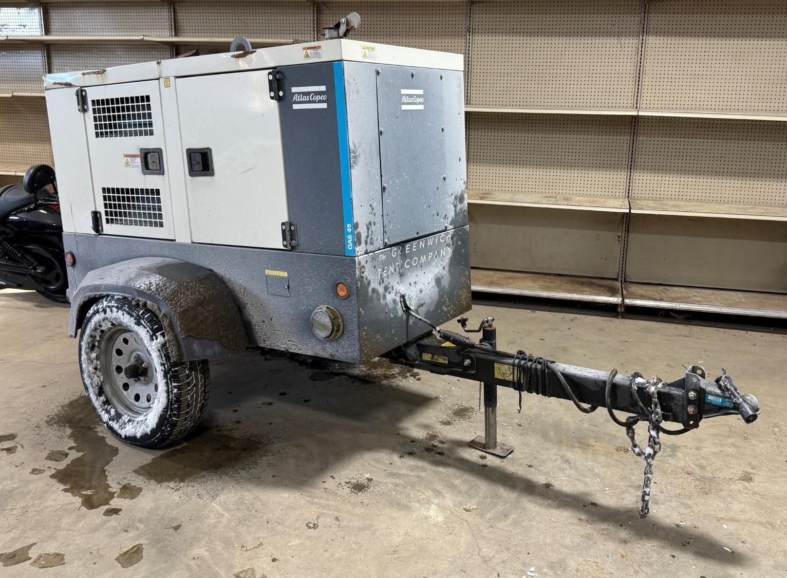 A trailer-mounted Atlas Copco air compressor, in a warehouse.
