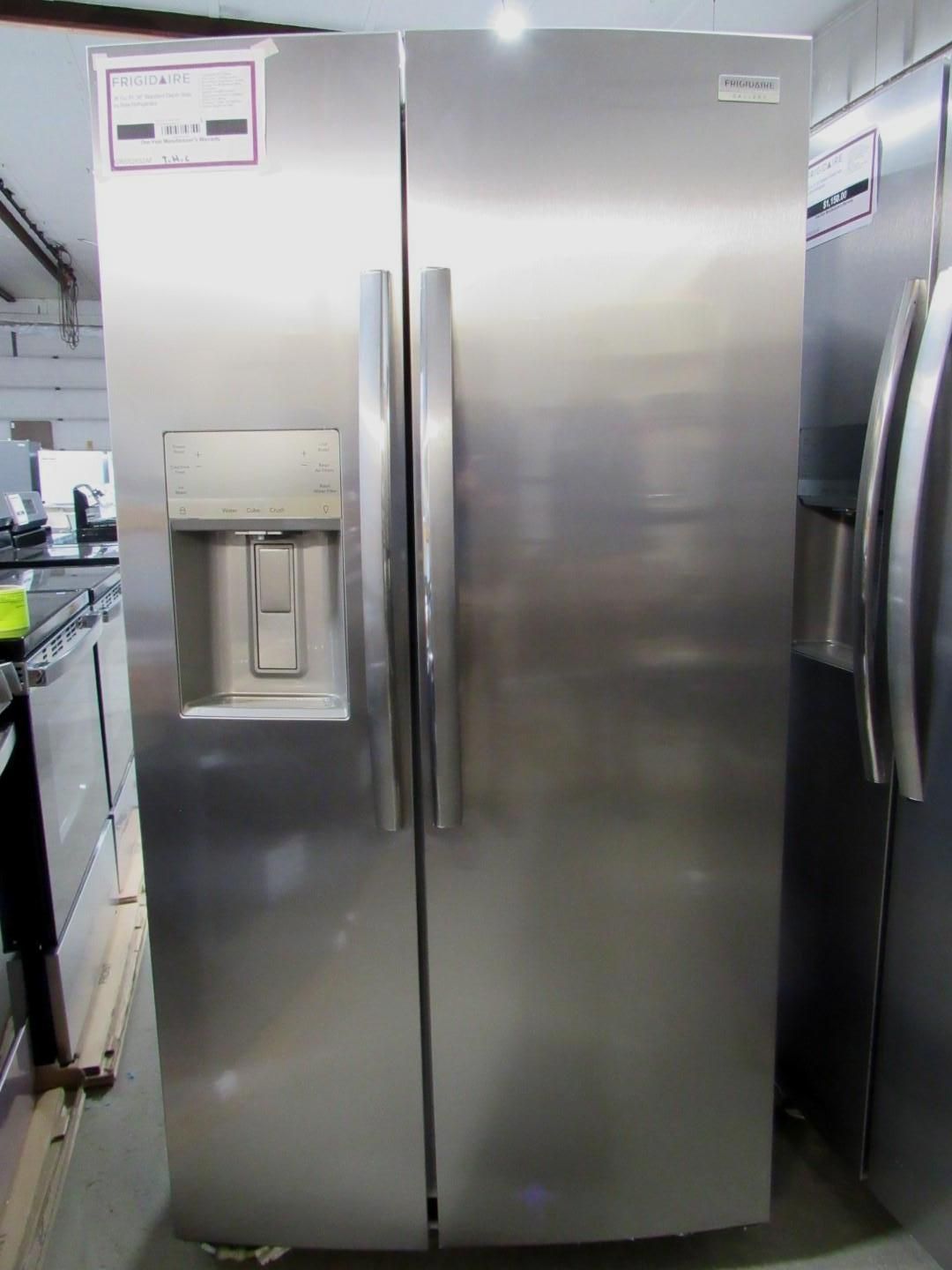 Stainless steel side-by-side refrigerator with water dispenser. In a store setting.