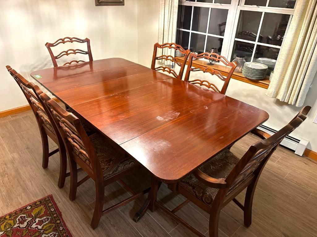 Dining table with six chairs in a room with a window and a rug.