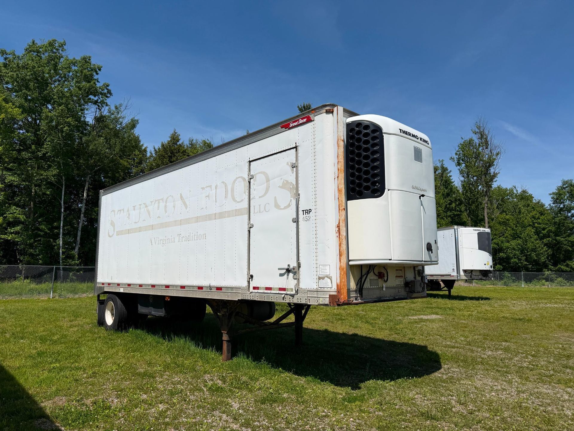 White refrigerated trailer on grass in a sunny field