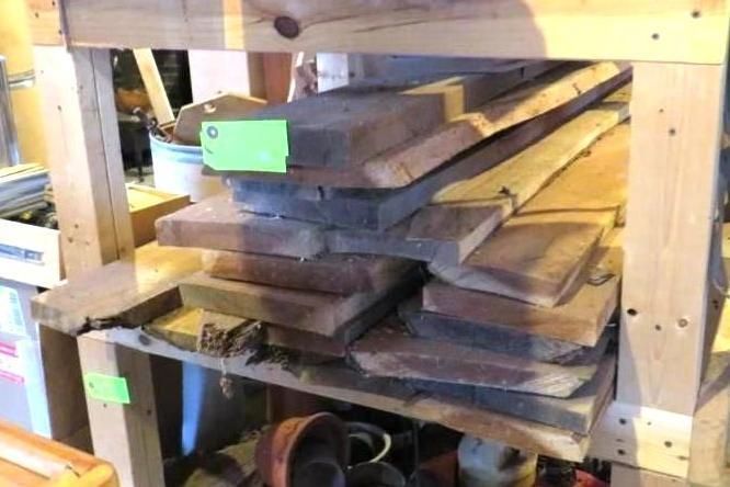 Wooden planks stacked on a wooden shelf, a workshop setting.