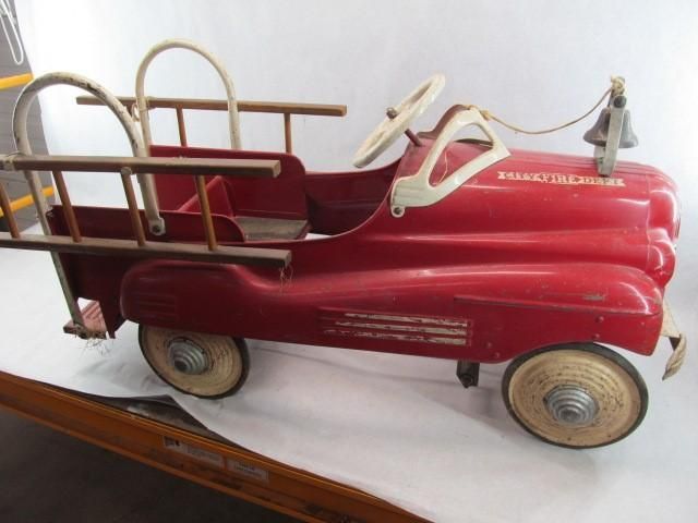 Red vintage pedal car shaped like a fire truck, with ladder and bell.