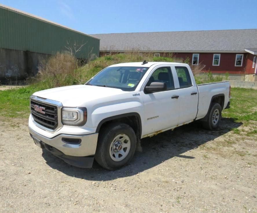 White GMC Sierra pickup truck parked on gravel in front of a barn.