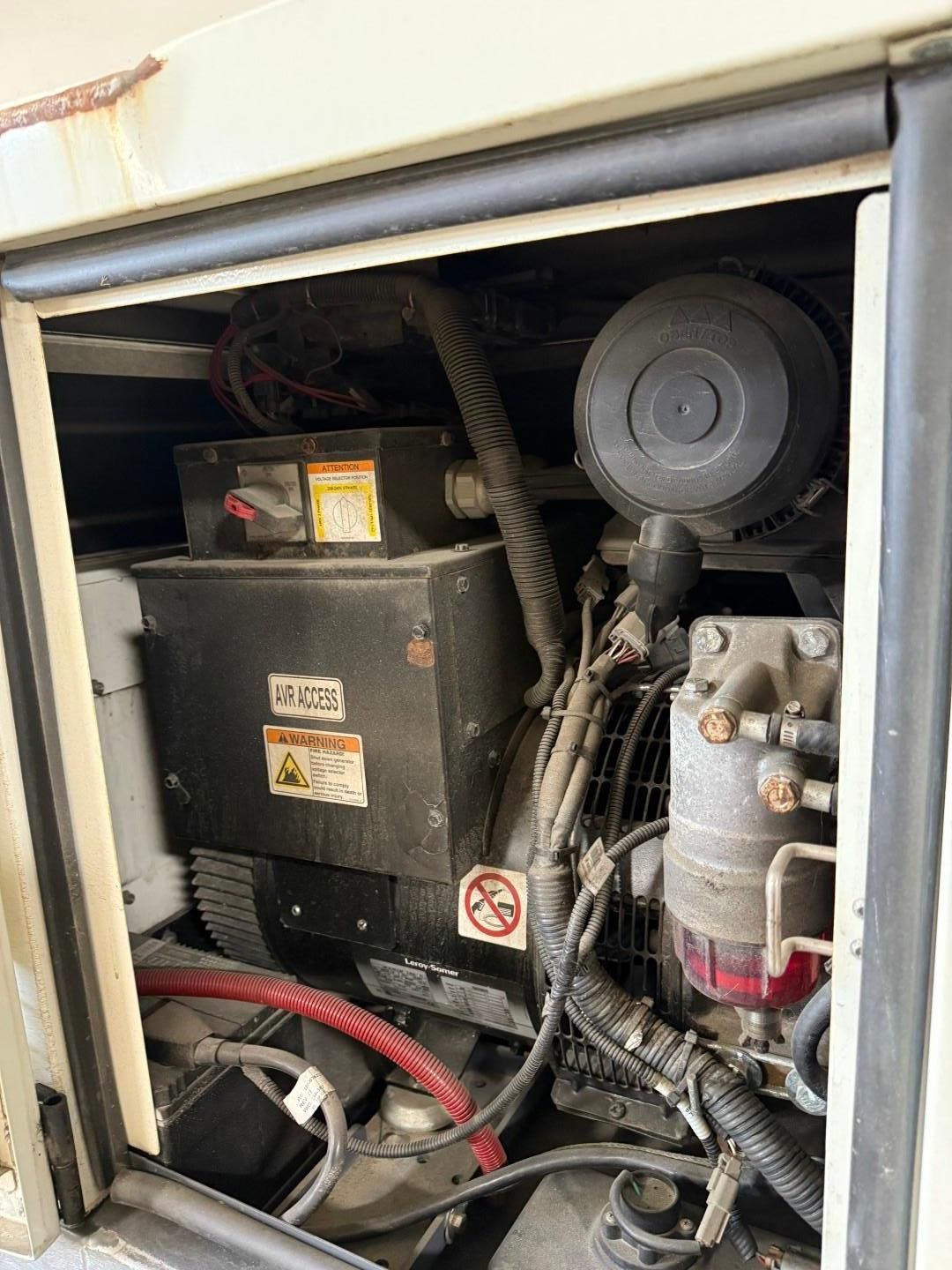 Open compartment of a generator. Black components with red and black wires, beige frame.