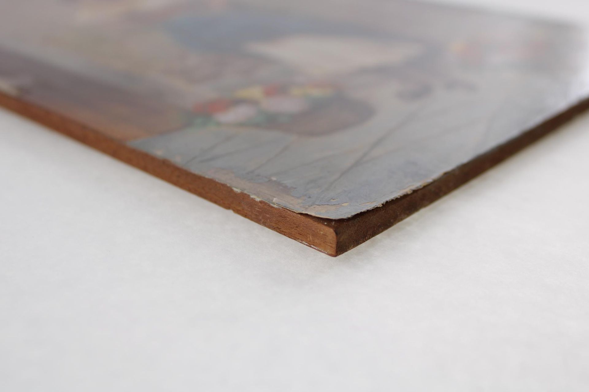 Close-up of a painted image on a wooden board; the brown edge of the board is visible.