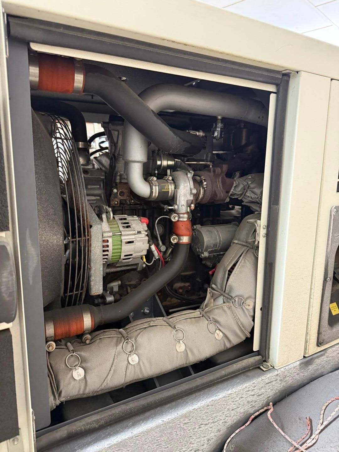Open view of a generator engine with a fan, turbocharger, and alternator.