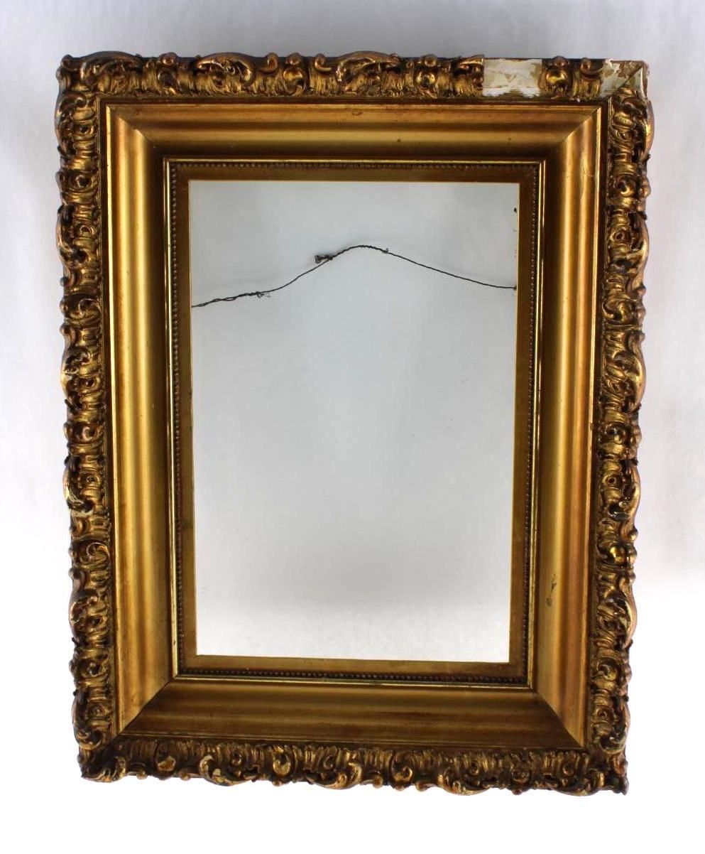 Ornate, gold-colored picture frame with an empty center and a hanging wire.