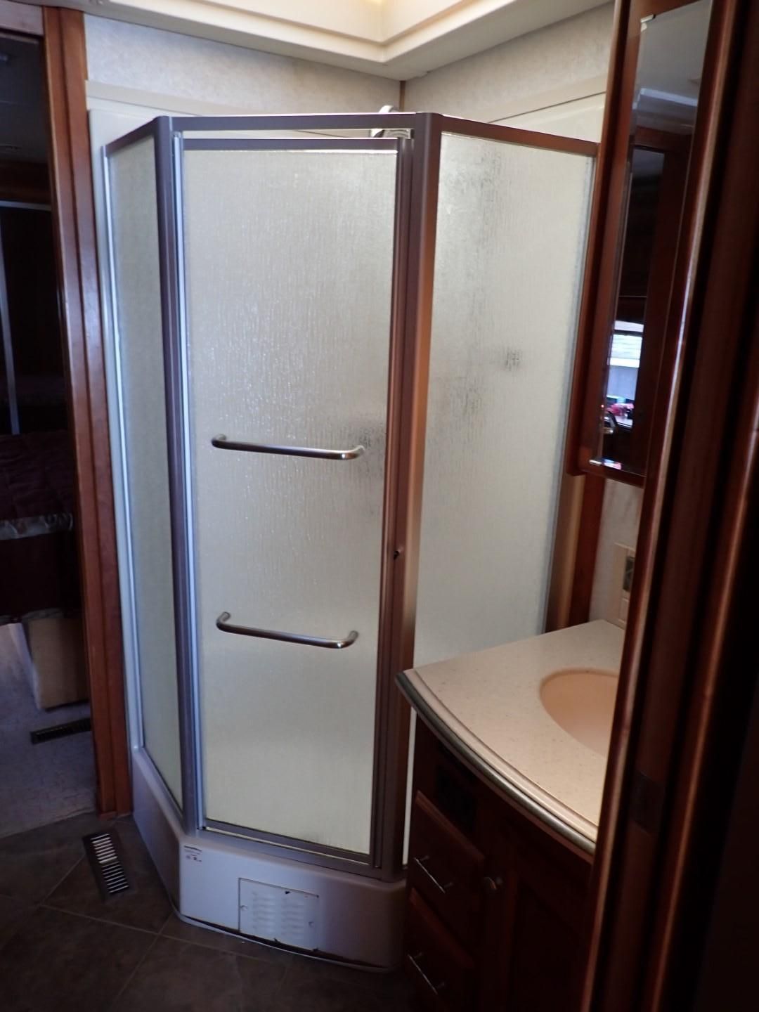 Corner shower in a motor home with a frosted glass door and a vanity.