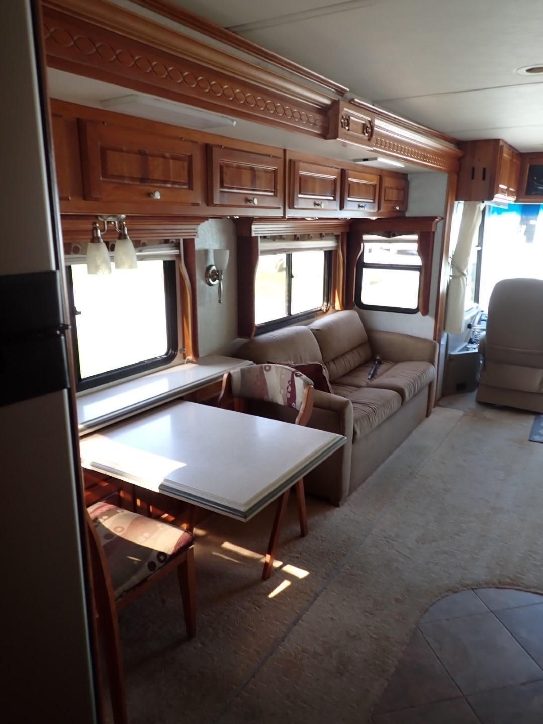 Interior of a recreational vehicle with a table, sofa, and overhead cabinets.
