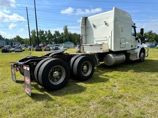White semi-truck parked on grass. Rear view shows wheels, fuel tank, and hitch.