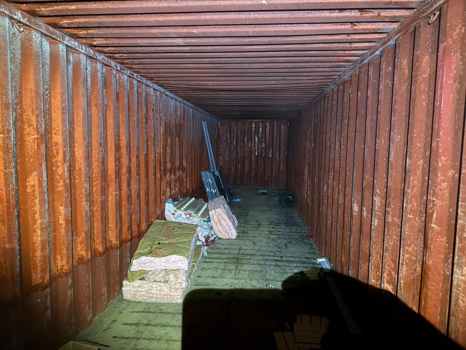Interior of a shipping container with some debris on the floor.
