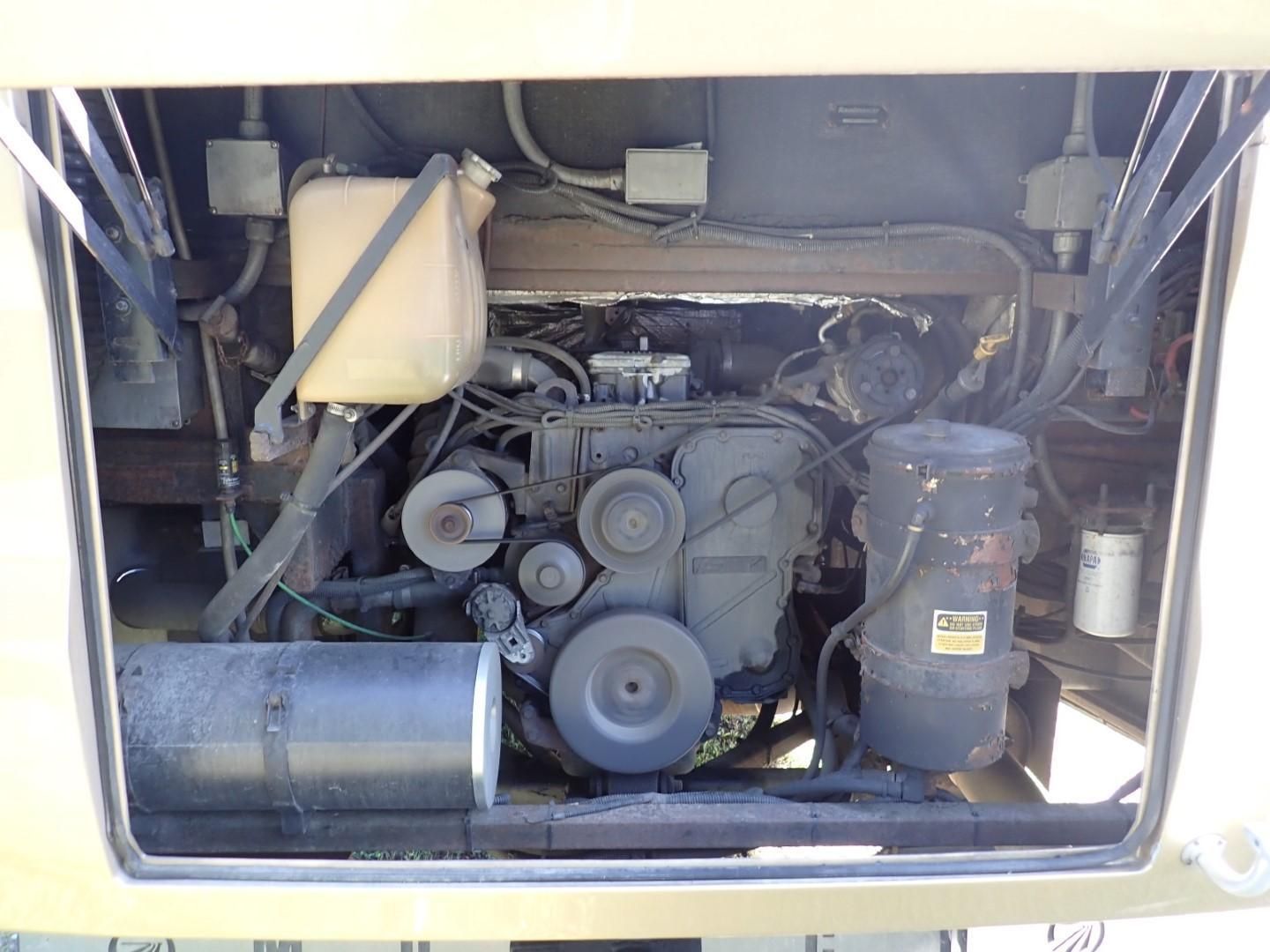 Engine compartment of a vehicle, showing various components, including an engine, belts, and reservoir.