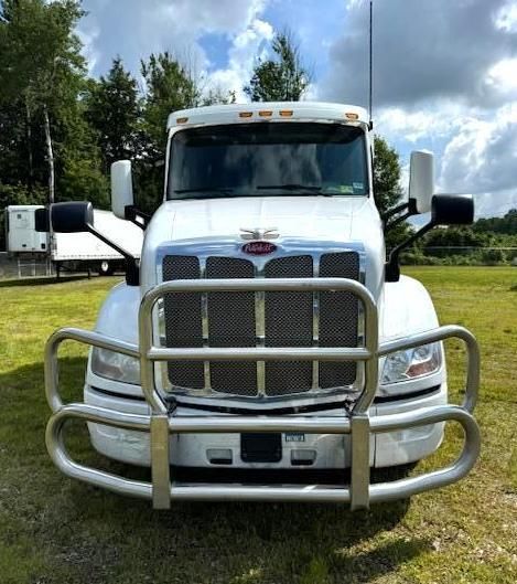 White Peterbilt semi-truck with chrome grill and bull bar parked outside on a sunny day.