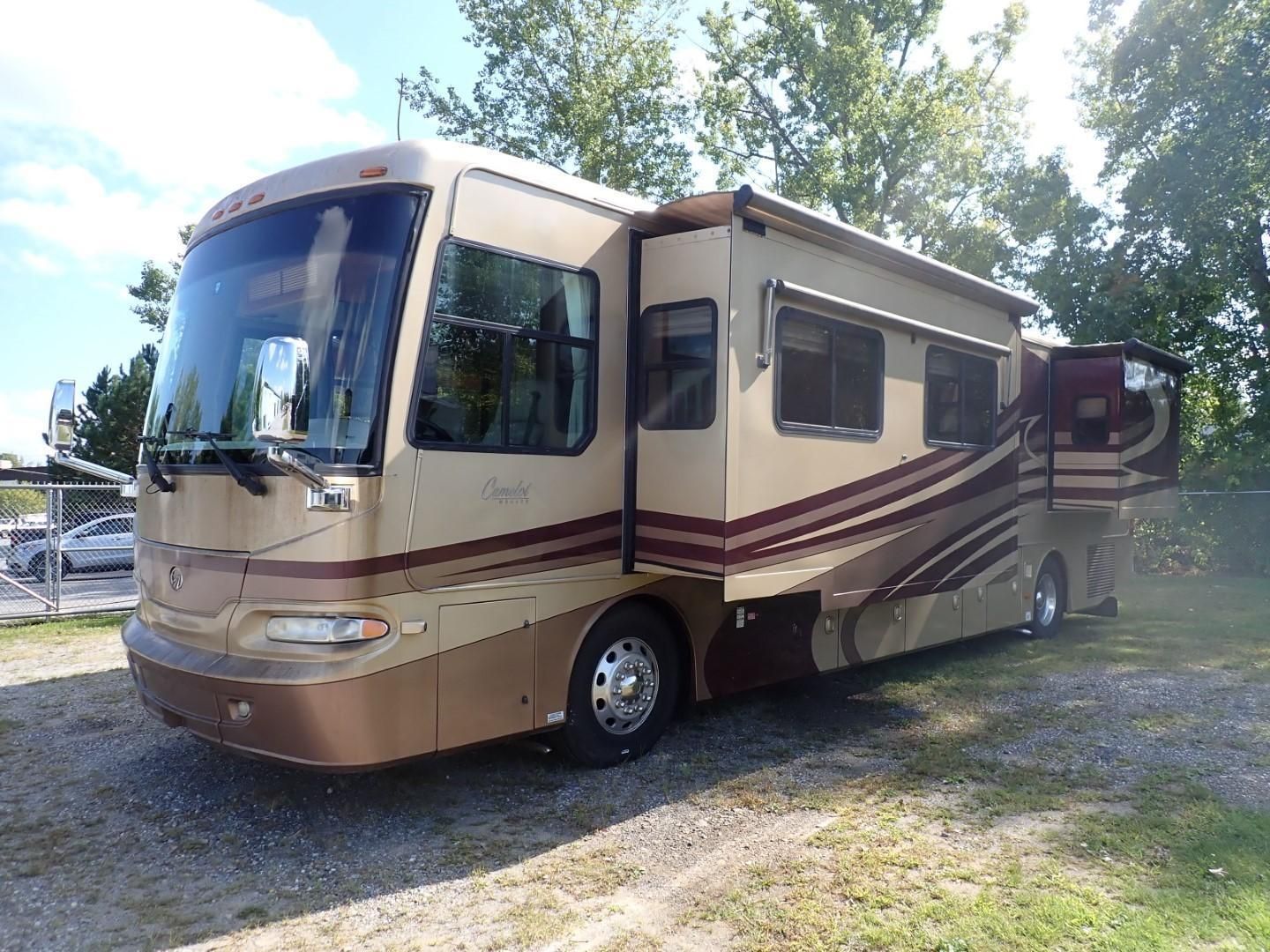 Tan and maroon RV parked on gravel.