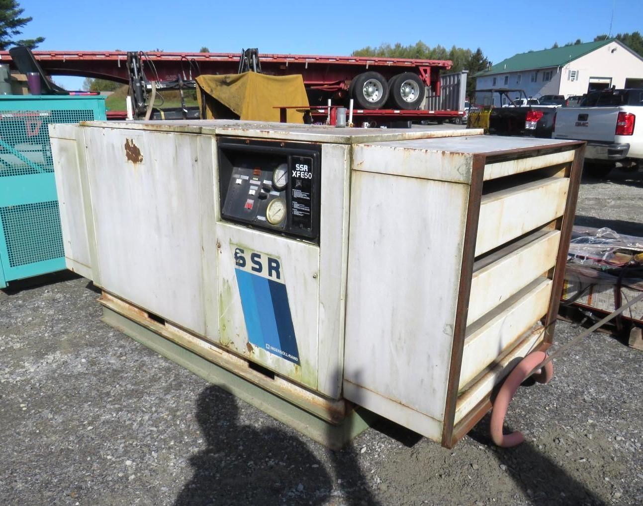 White industrial air compressor unit with blue and black panel; outside setting.