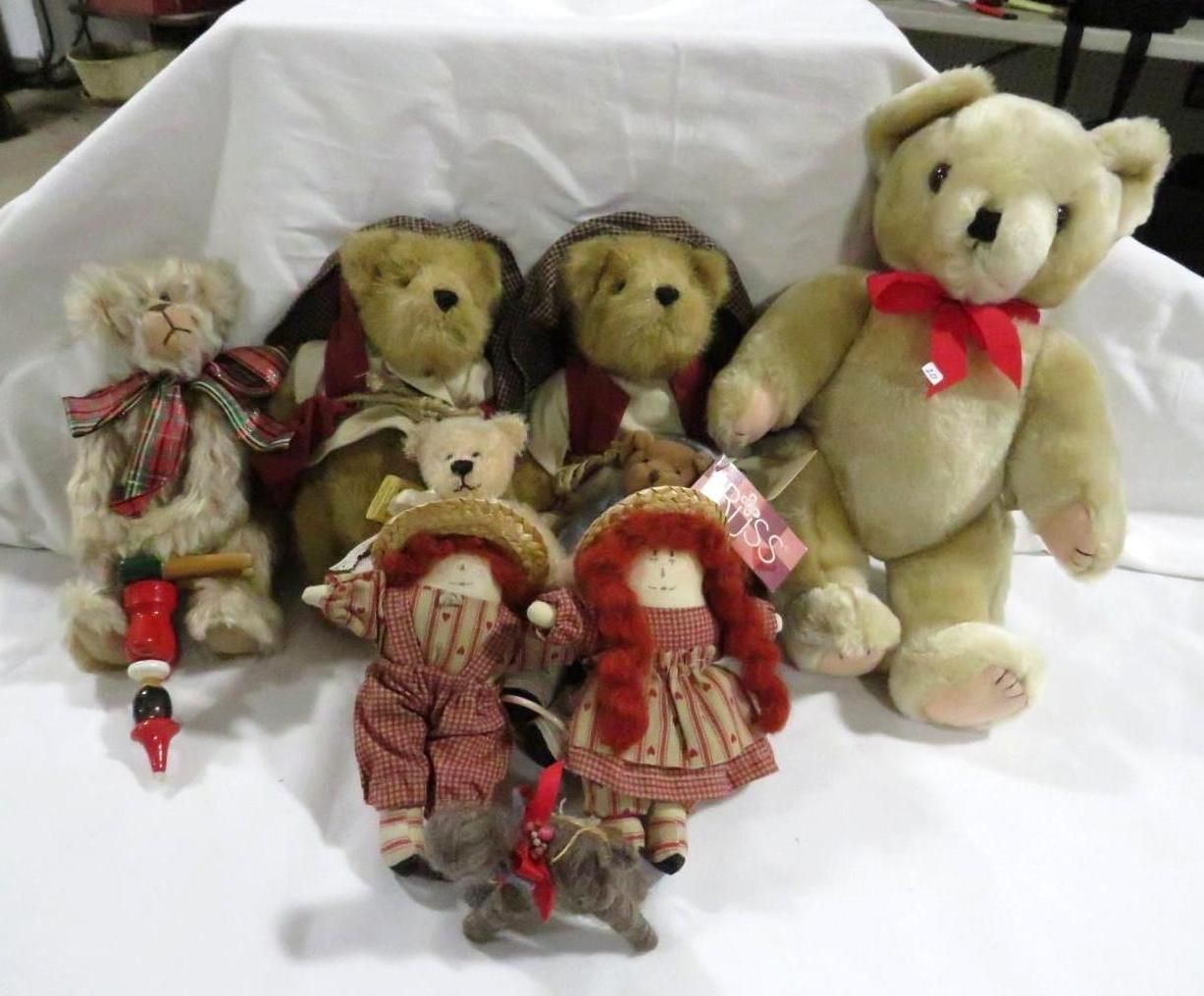 A collection of teddy bears and small dolls arranged on a white surface.