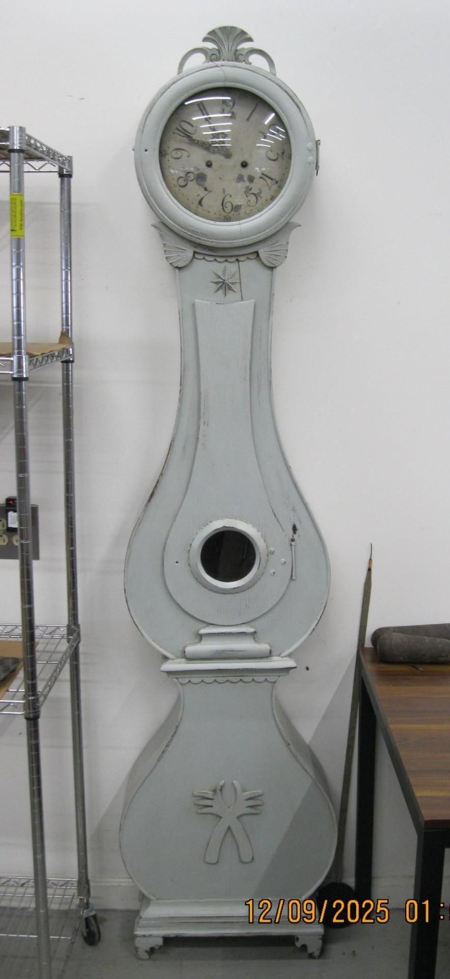 A tall, light-gray grandfather clock.