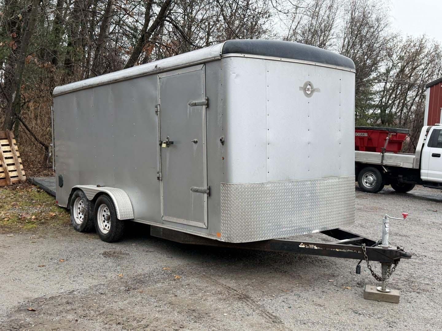 Silver enclosed cargo trailer with a black roof and diamond plate front.