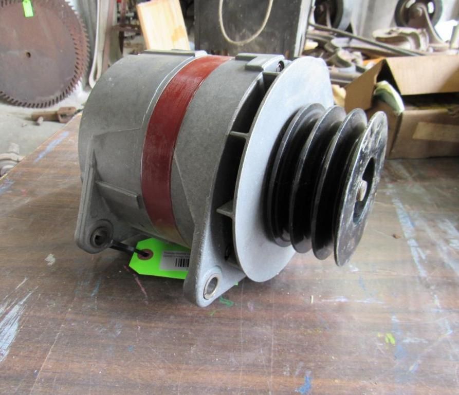 Gray alternator with a black pulley on a wooden surface.