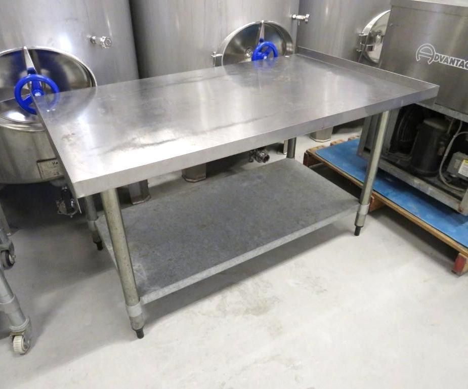 Stainless steel work table with a lower shelf, in a commercial setting.