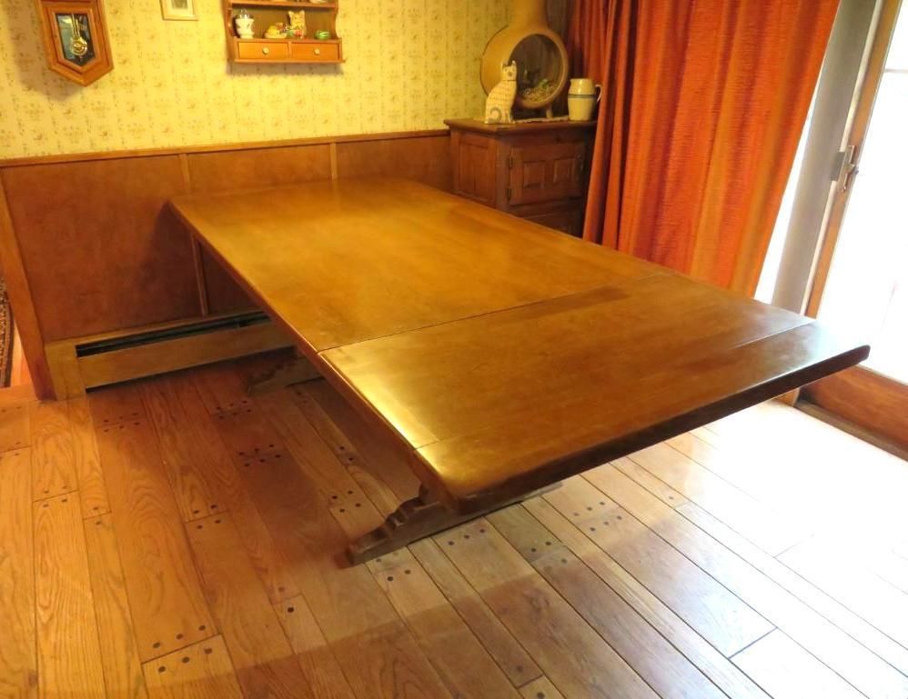 Wooden dining table in a room with hardwood floors and an attached wall. Sunlight through the window.