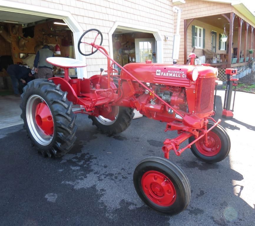 Red Farmall Cub tractor parked on asphalt.