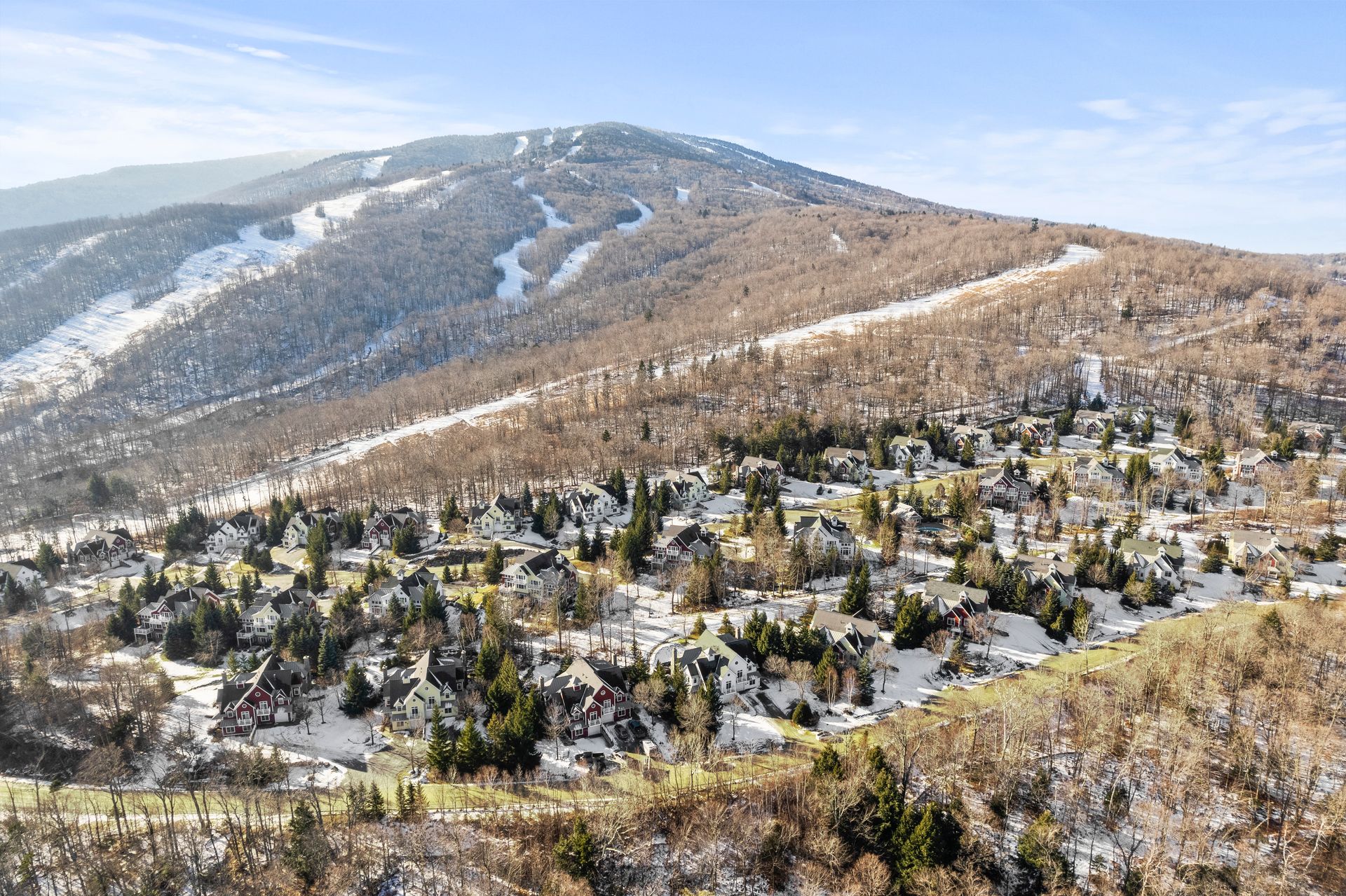 Mountain landscape with snowy ski slopes and a village nestled below.