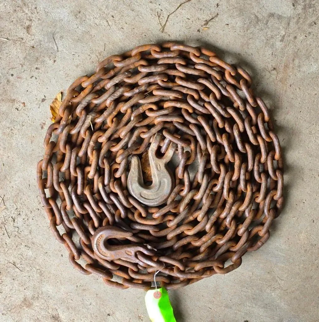 Coiled metal chain with hooks on a concrete floor.
