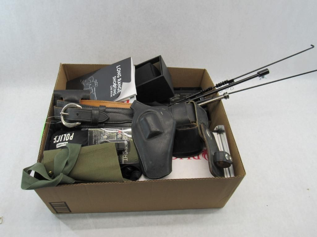 Cardboard box filled with gear: holster, belt, manual, metal rods, and other items.