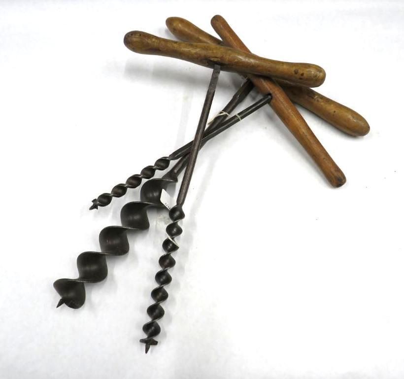Hand-powered auger drills with wooden handles, on a white surface.