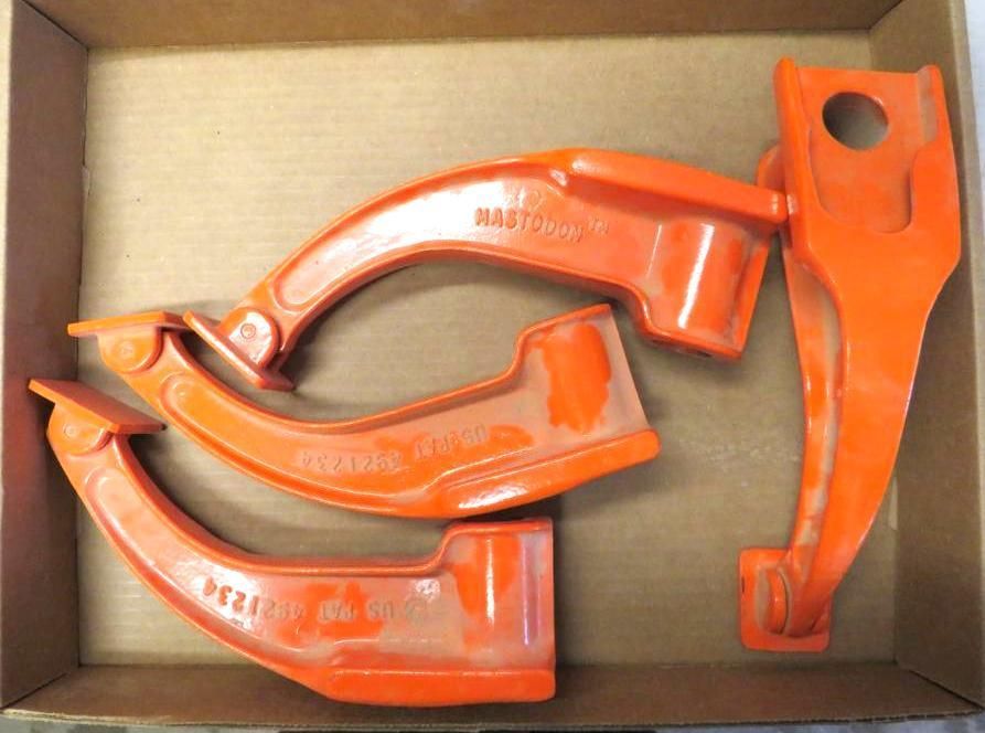 Four orange, curved metal clamp tools in a cardboard box.