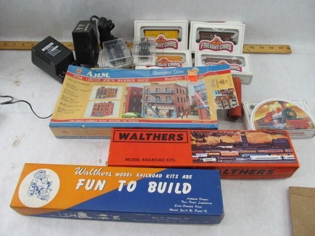 Various model railroad kits, including buildings, power supply, and accessories, on a white surface.