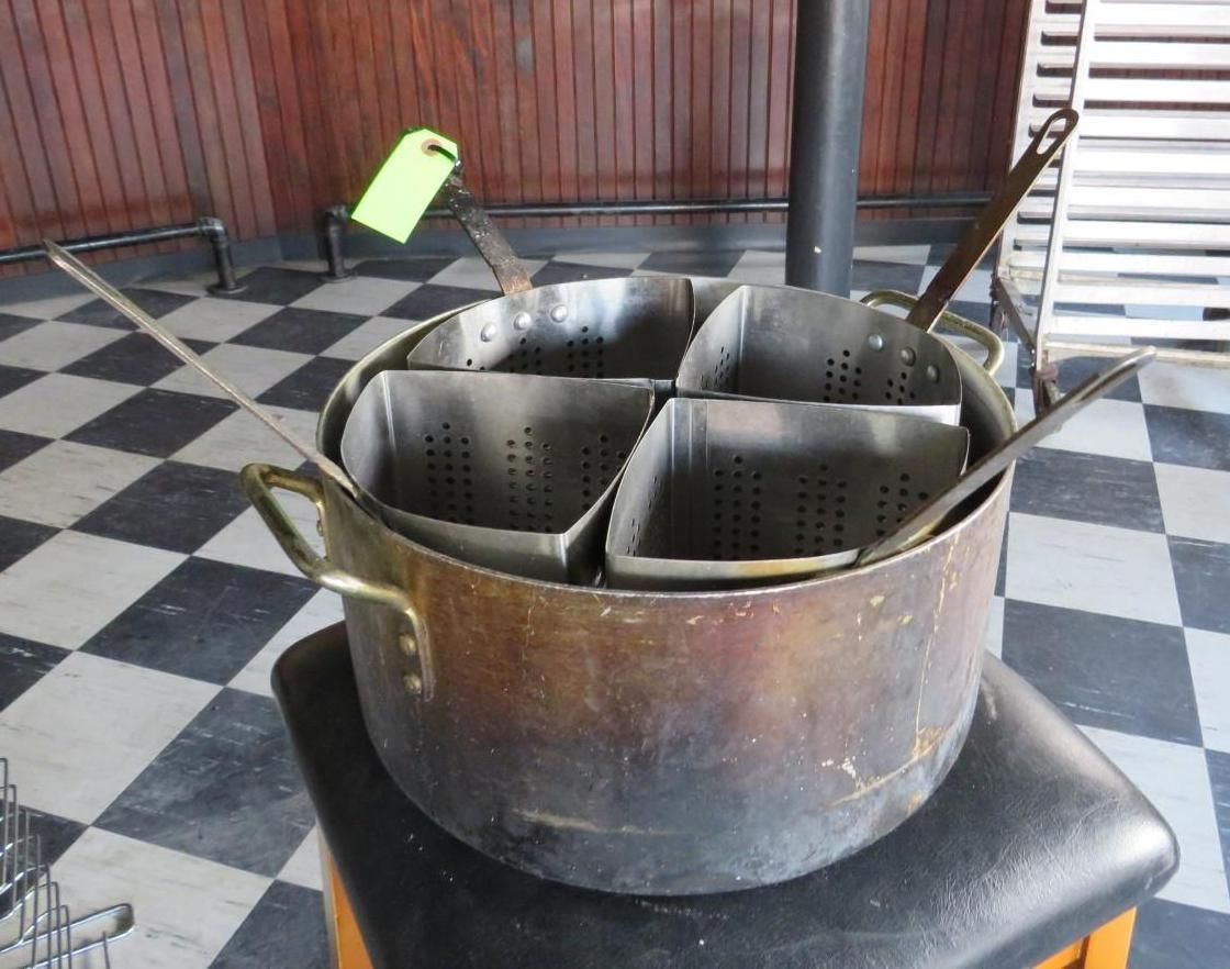 A large pot with four individual pasta strainer baskets inside, on a checkered floor.
