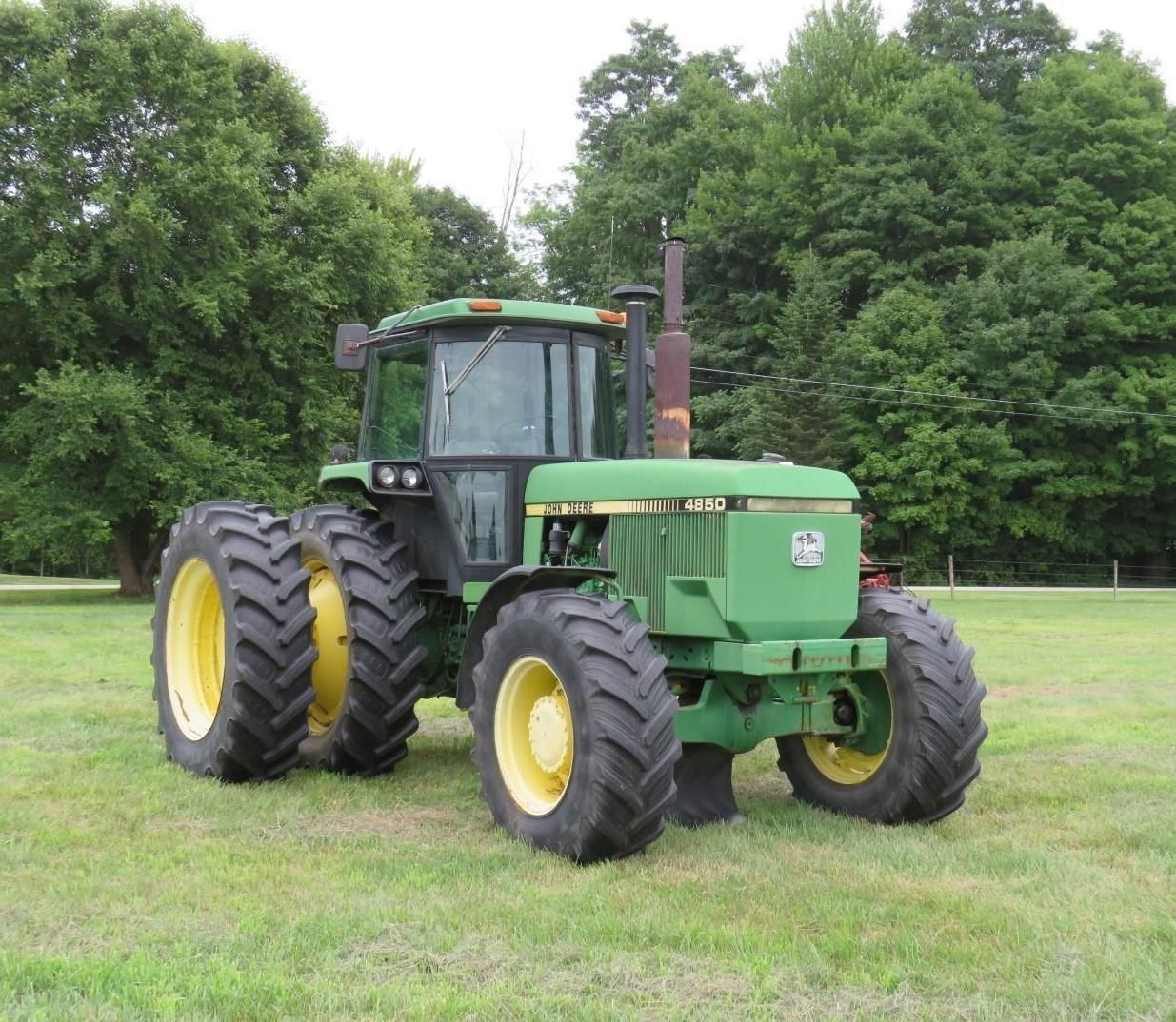 Green John Deere tractor parked on grass field.